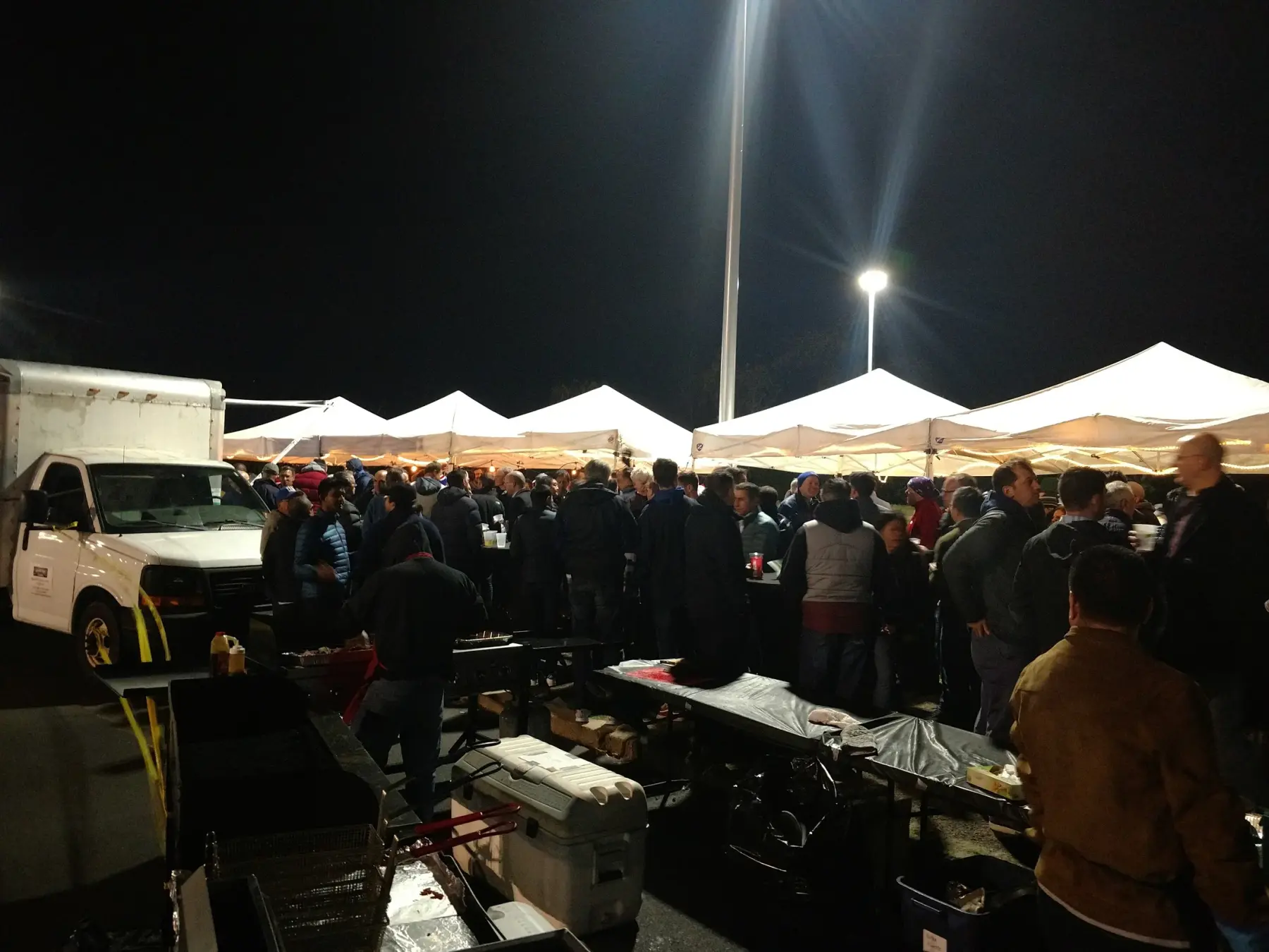 Lit Gametime tents and a crowd at a night event