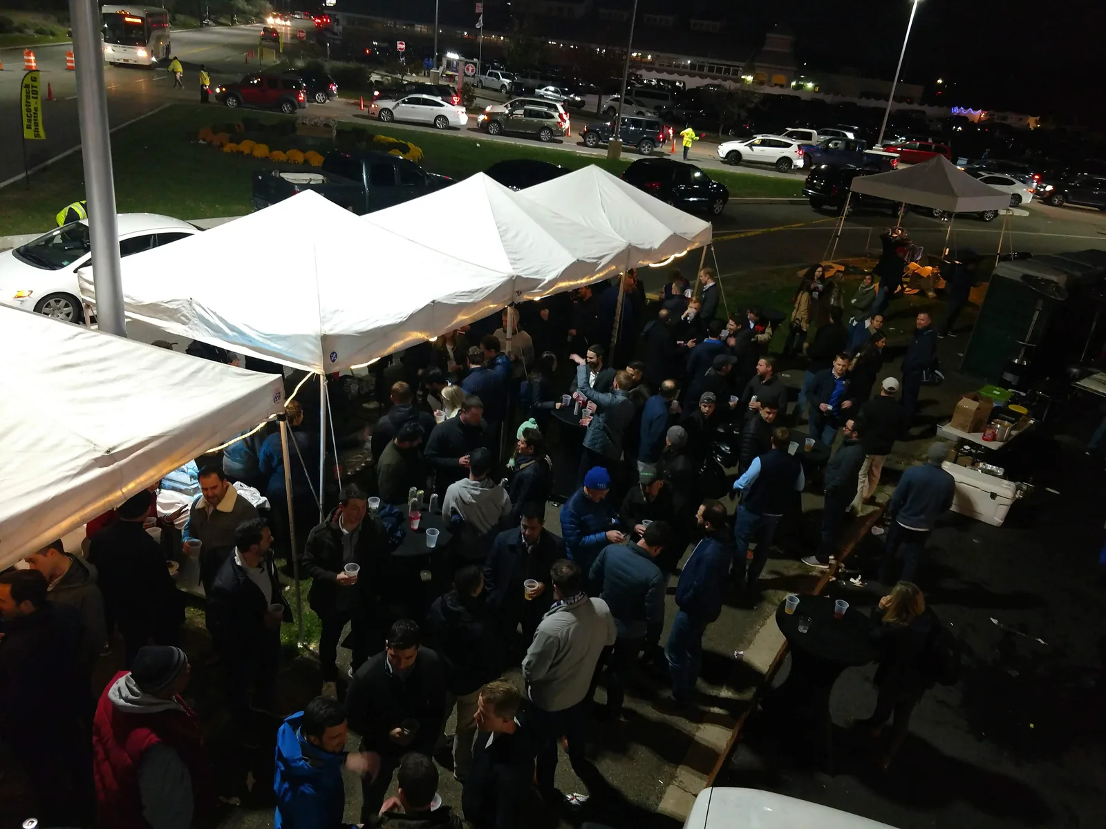 A tailgate crowd under the lights at a night game