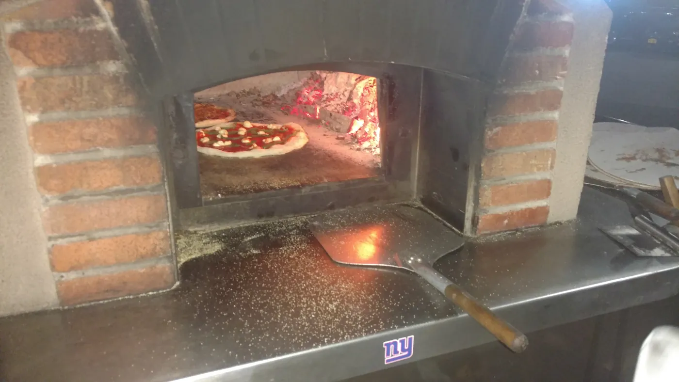 A wood-fired oven cooking pizza at a tailgate