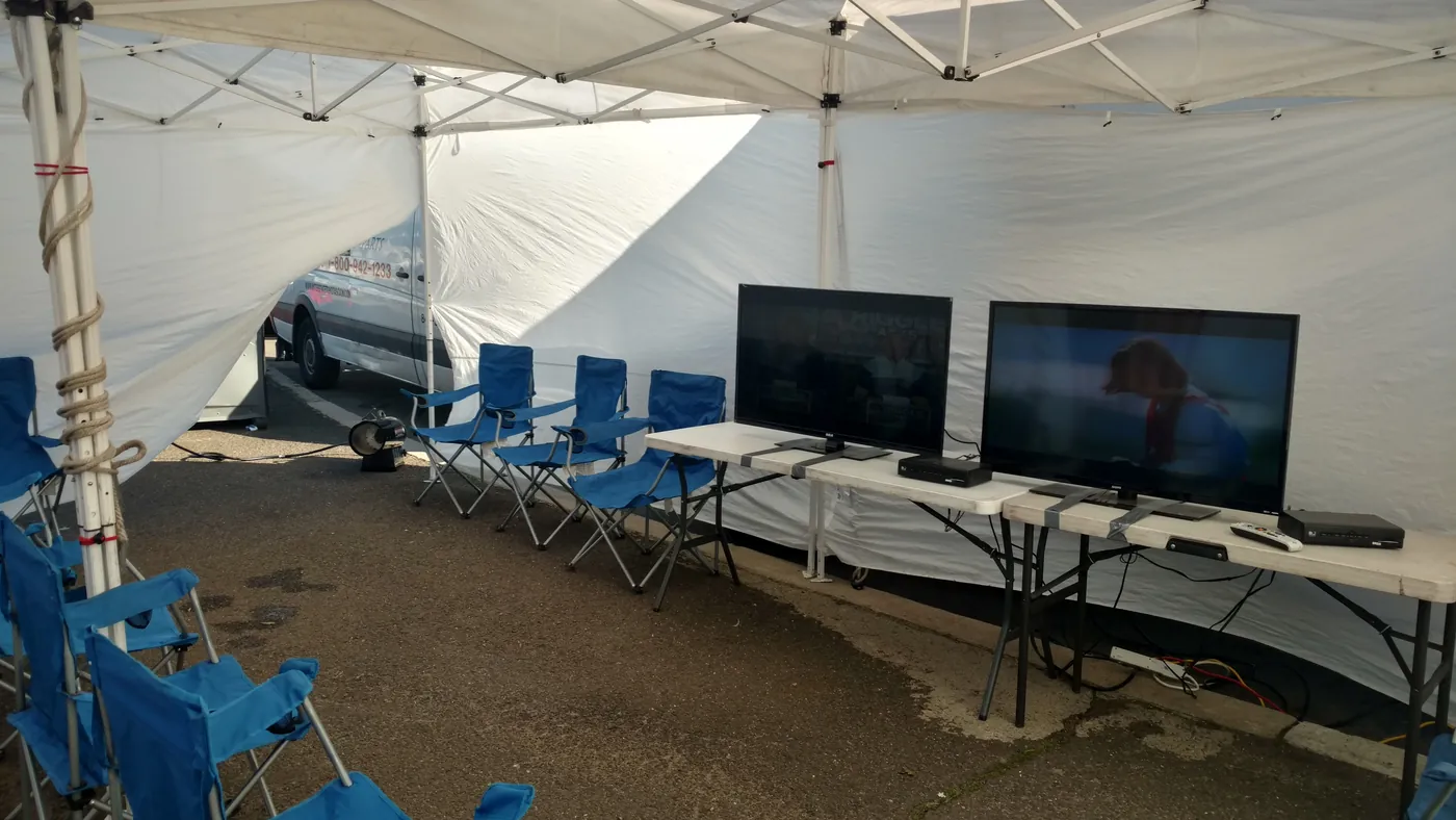 Flat-screen TVs set up under the tailgate tent